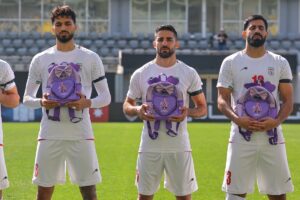 Iran wear black armbands and hold schoolbags during national anthem before match