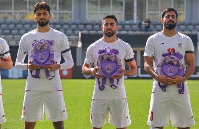 Iran wear black armbands and hold schoolbags during national anthem before match
